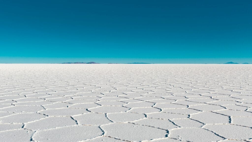 Vast salar with geometric patterns under a clear blue sky in Bolivia's Uyuni.