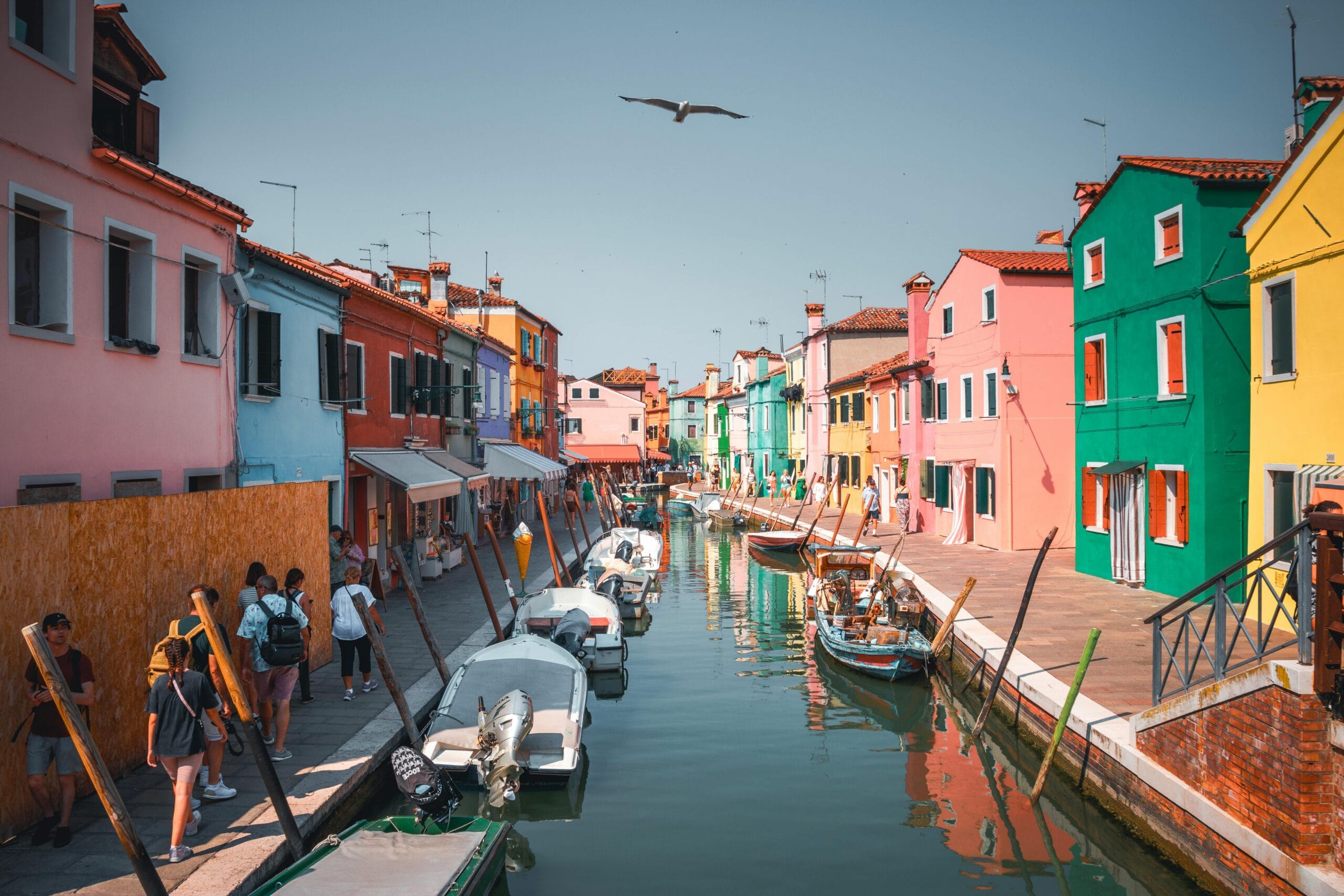 Vibrant houses along Burano's canal in Venice, Italy, under a clear blue sky.