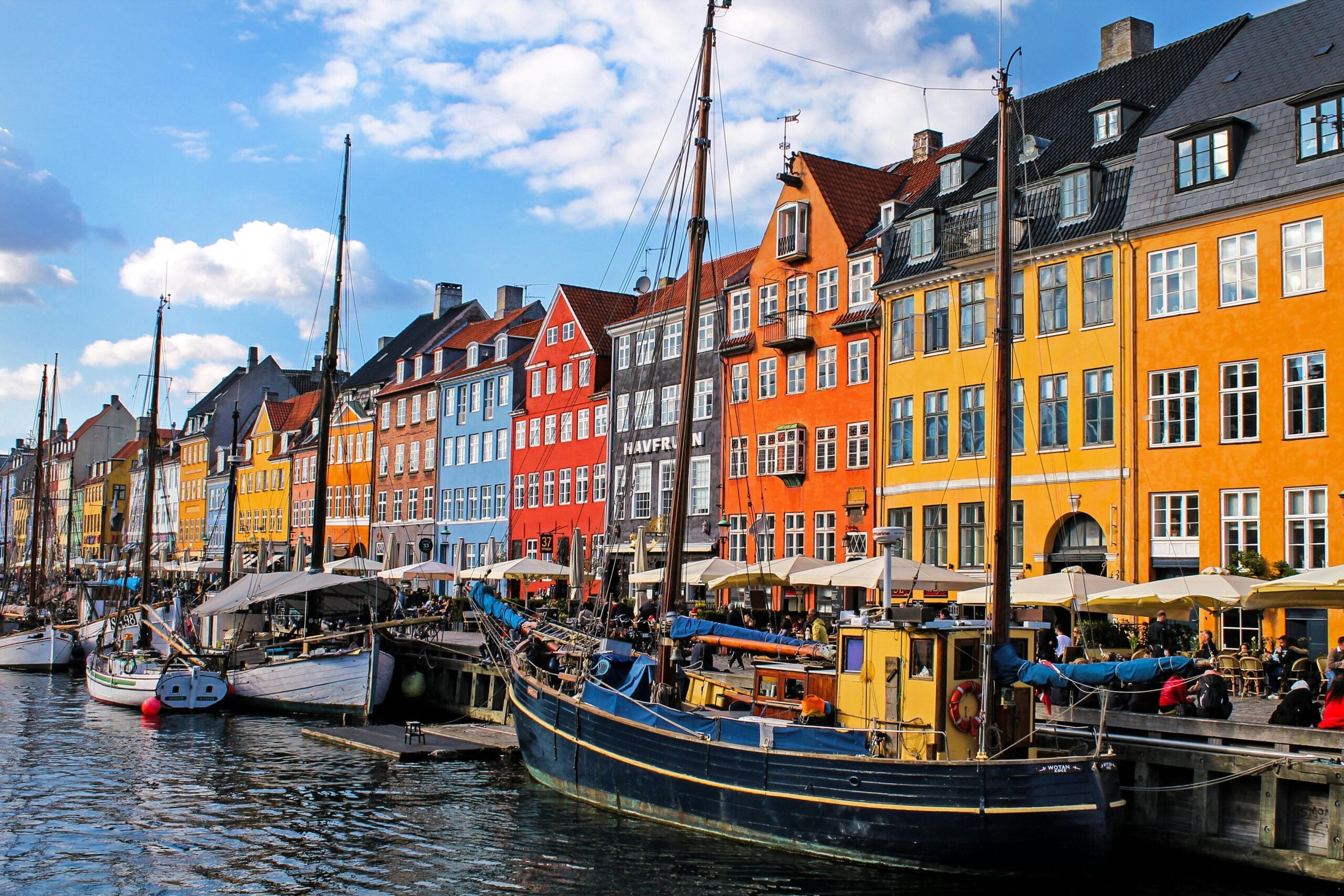 A colorful view of Nyhavn, Copenhagen's iconic waterfront with historic buildings and moored boats.