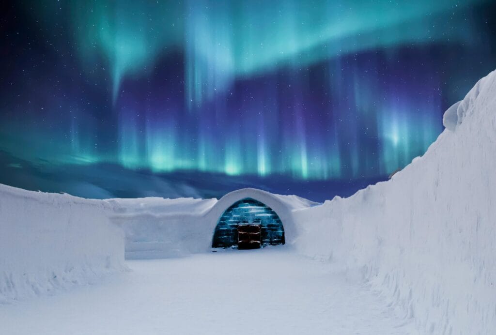Captivating northern lights illuminate a snowy igloo in the Arctic landscape at night.
